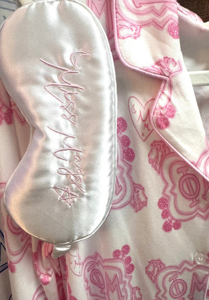Silky sleep mask with 'Miss Mags' embroidery on a pink patterned fabric background